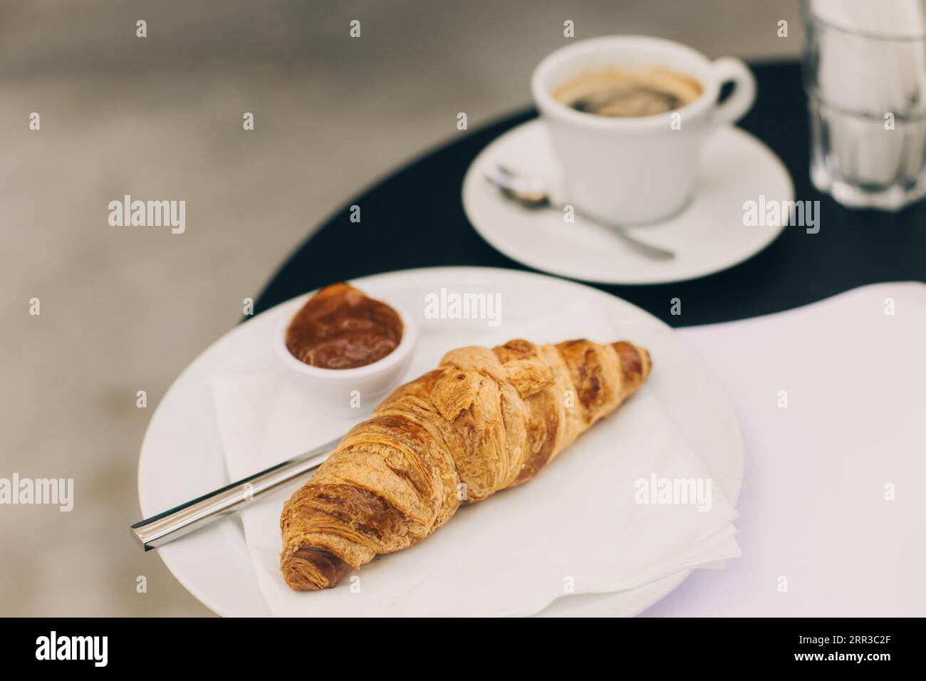 Une tasse de café noir et un croissant sur une table dans un café de rue. Mise au point sélective. Placer pour le texte. Banque D'Images