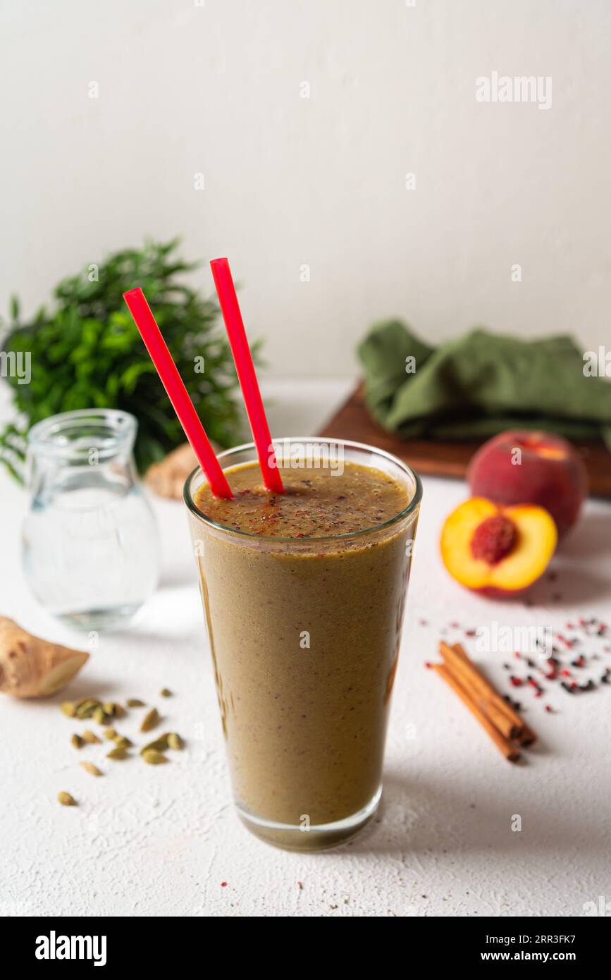 Smoothie aux nectarines, cannelle et cardamome. Smoothie aux fruits sains dans un verre avec de la paille à boire. Banque D'Images