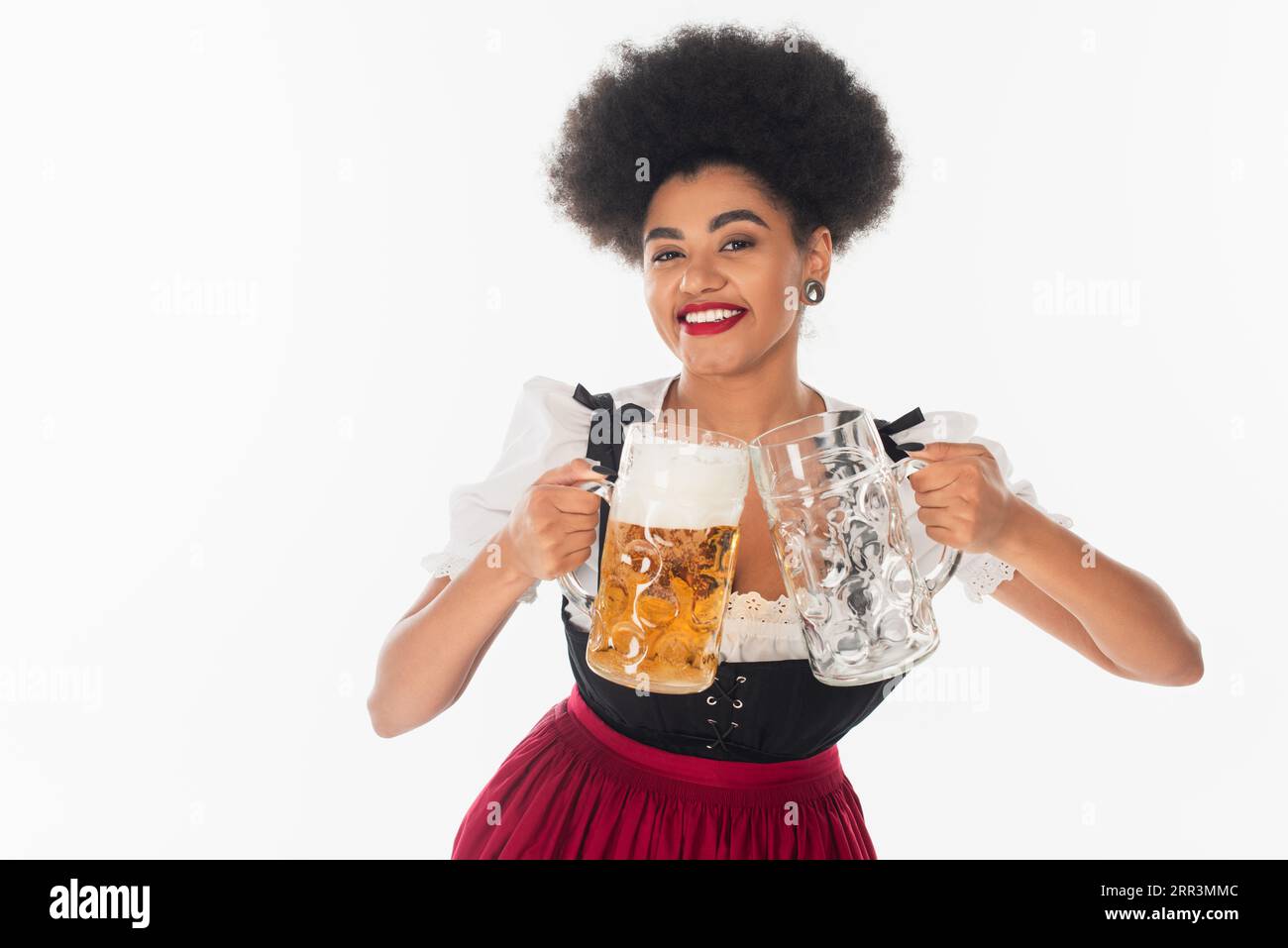 serveuse bavaroise afro-américaine heureuse avec des tasses à bière pleines et vides sur blanc, oktoberfest Banque D'Images