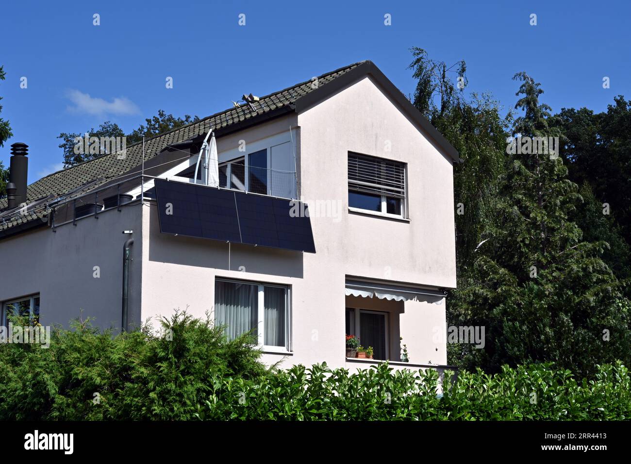 Panneaux solaires ou plaques photovoltaïques installés sur le balcon d'une maison familiale observée dans un village suisse. Banque D'Images