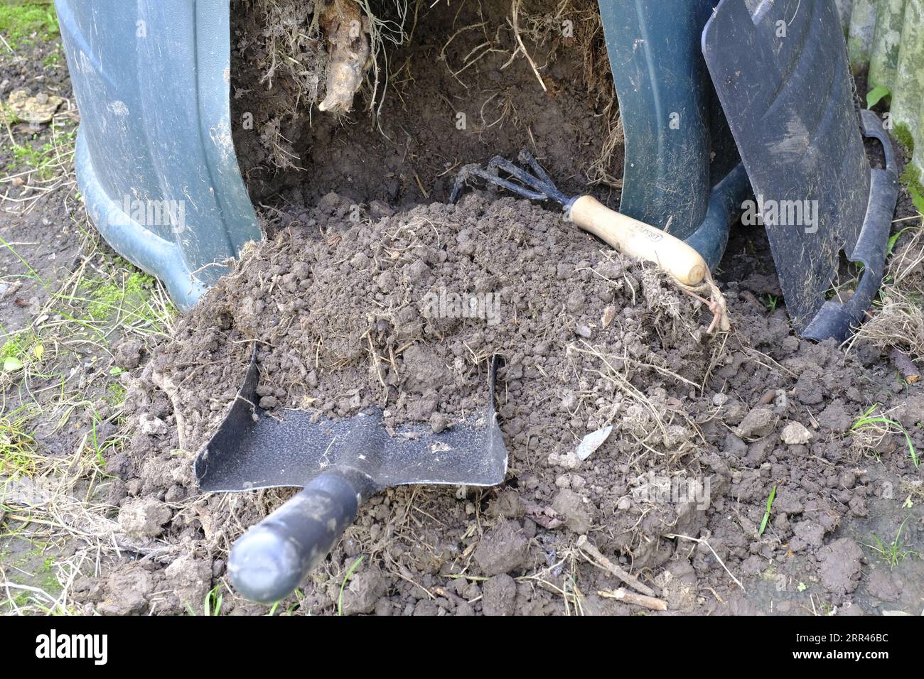 Bac à compost vidé par le bas à l'aide d'une pelle et d'une griffe de jardin pour détacher le sol Banque D'Images