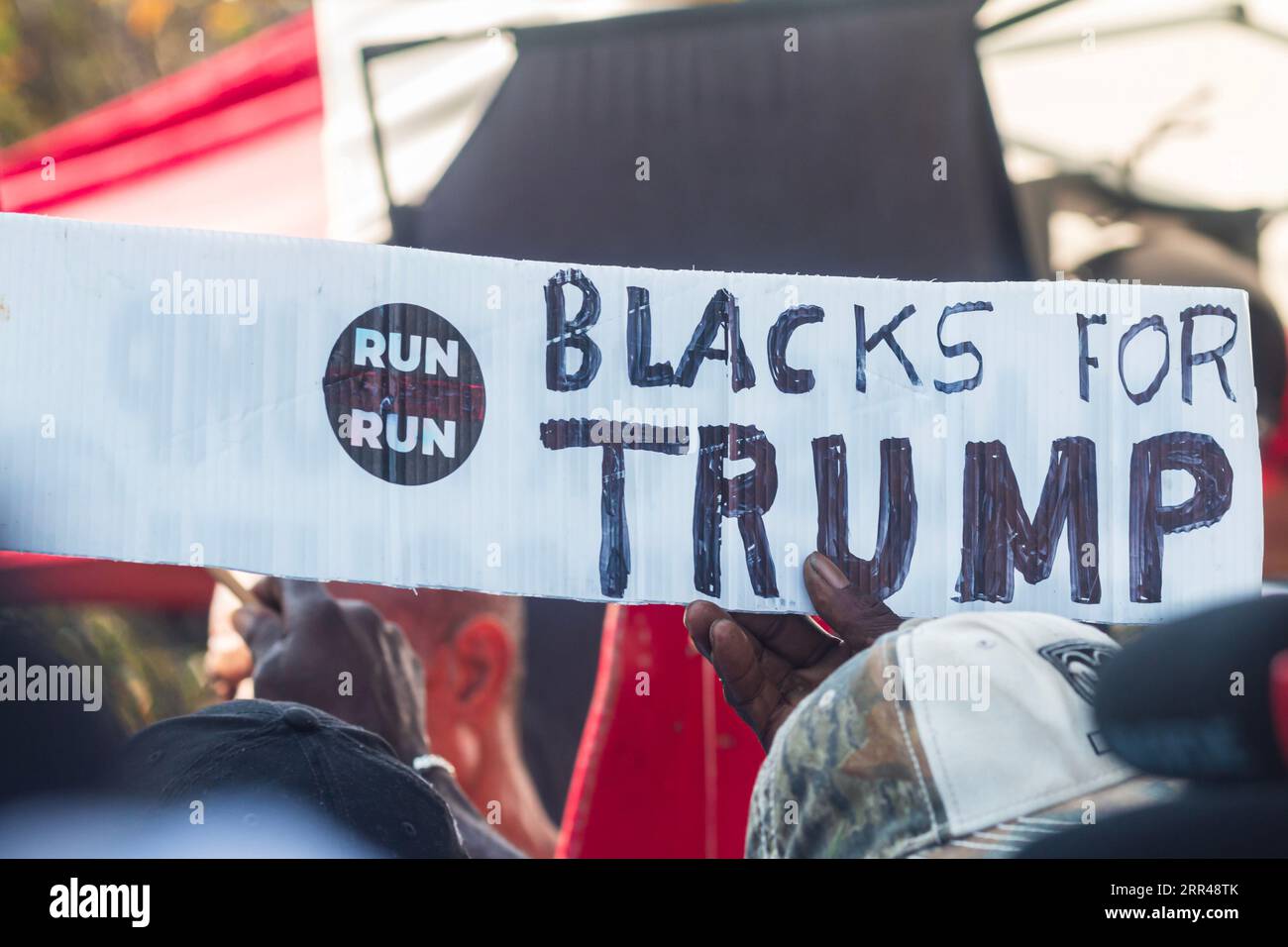 Un homme afro-américain tient une pancarte faite à la main qui dit « Noirs pour Trump » en attendant que Donald Trump soit arrêté à la prison du comté de Fulton. Banque D'Images