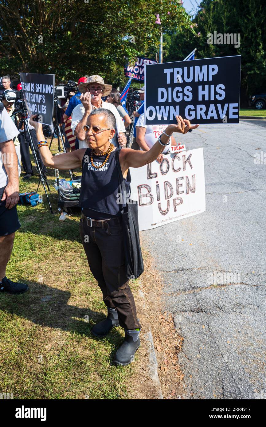 Atlanta, GA / États-Unis - 24 août 2023 : une femme tient des pancartes anti-Trump, tandis qu'un homme tient un pancarte anti-Biden, attendant l'arrestation de Donald Trump en Géorgie. Banque D'Images