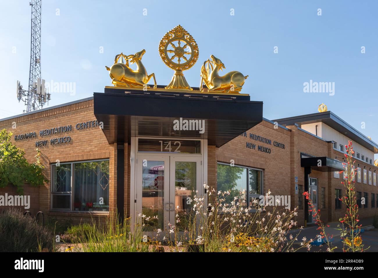 Extérieur du Centre de méditation Kadampa Nouveau Mexique, un bâtiment en briques d'un étage avec des symboles bouddhistes dorés, dharmacharka et cerfs, Albuquerque, États-Unis. Banque D'Images