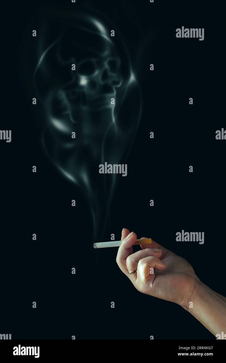 La main humaine tient une cigarette. Fumée en forme de crâne. Fumer tue. Isolé sur noir. Banque D'Images
