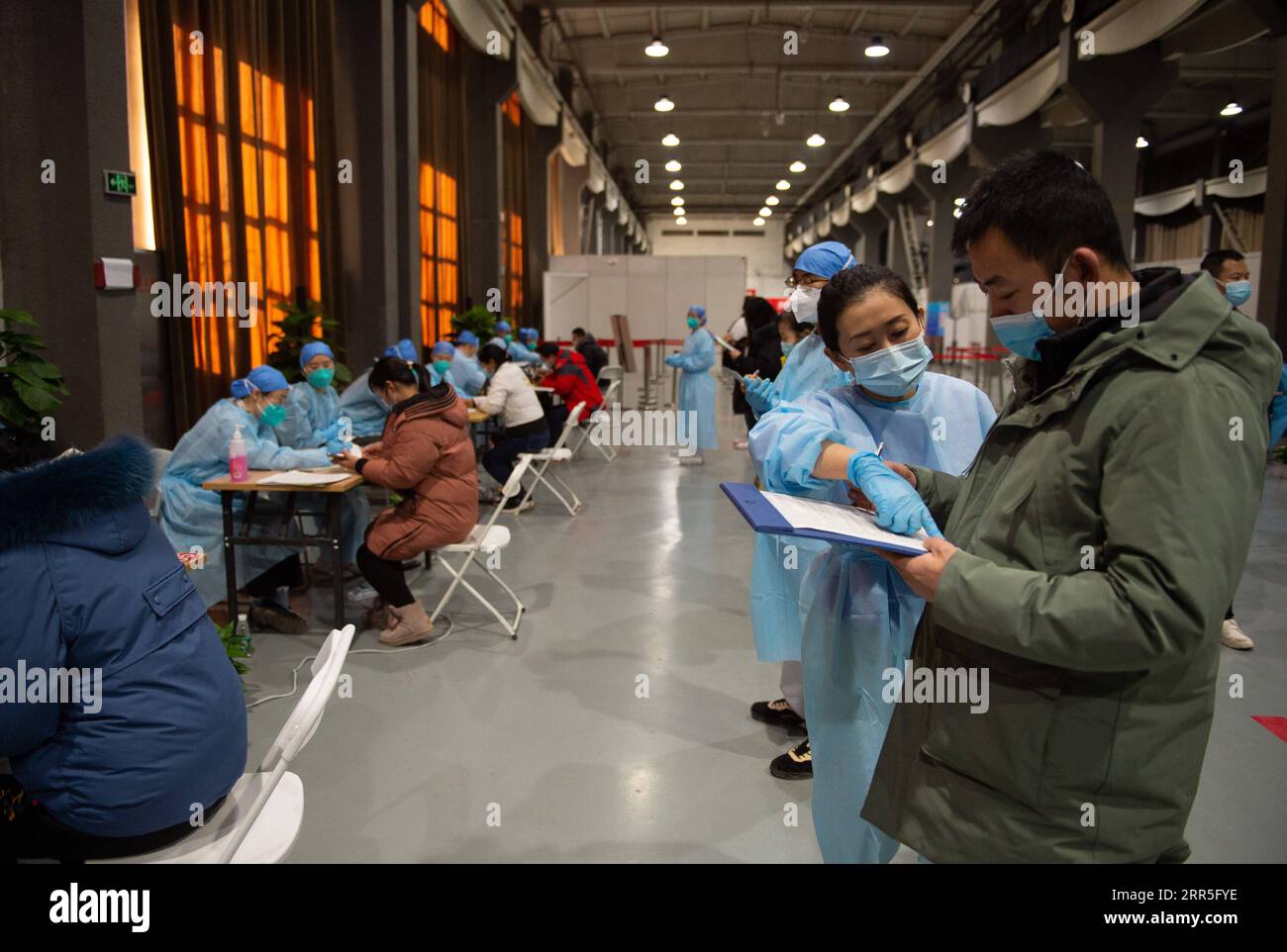 210106 -- BEIJING, le 6 janvier 2021 -- M. Wu R remplit une lettre de consentement éclairé sous la direction d'un membre du personnel avant de recevoir une injection de vaccin COVID-19 sur un site d'inoculation dans le district de Chaoyang, Beijing, capitale de la Chine, le 5 janvier 2021. Avec plus de 70 de ses collègues dans le secteur de la transformation des aliments, M. Wu dont le prénom est omis pour la protection de la vie privée, 40, est monté à bord d'une navette qui les amènerait à un site de vaccination vers 1 heures mardi. Wu, qui travaille pour une entreprise impliquée dans la pâtisserie, la boulangerie et le transport de la chaîne du froid, a déclaré tous ses collègues sauf t Banque D'Images