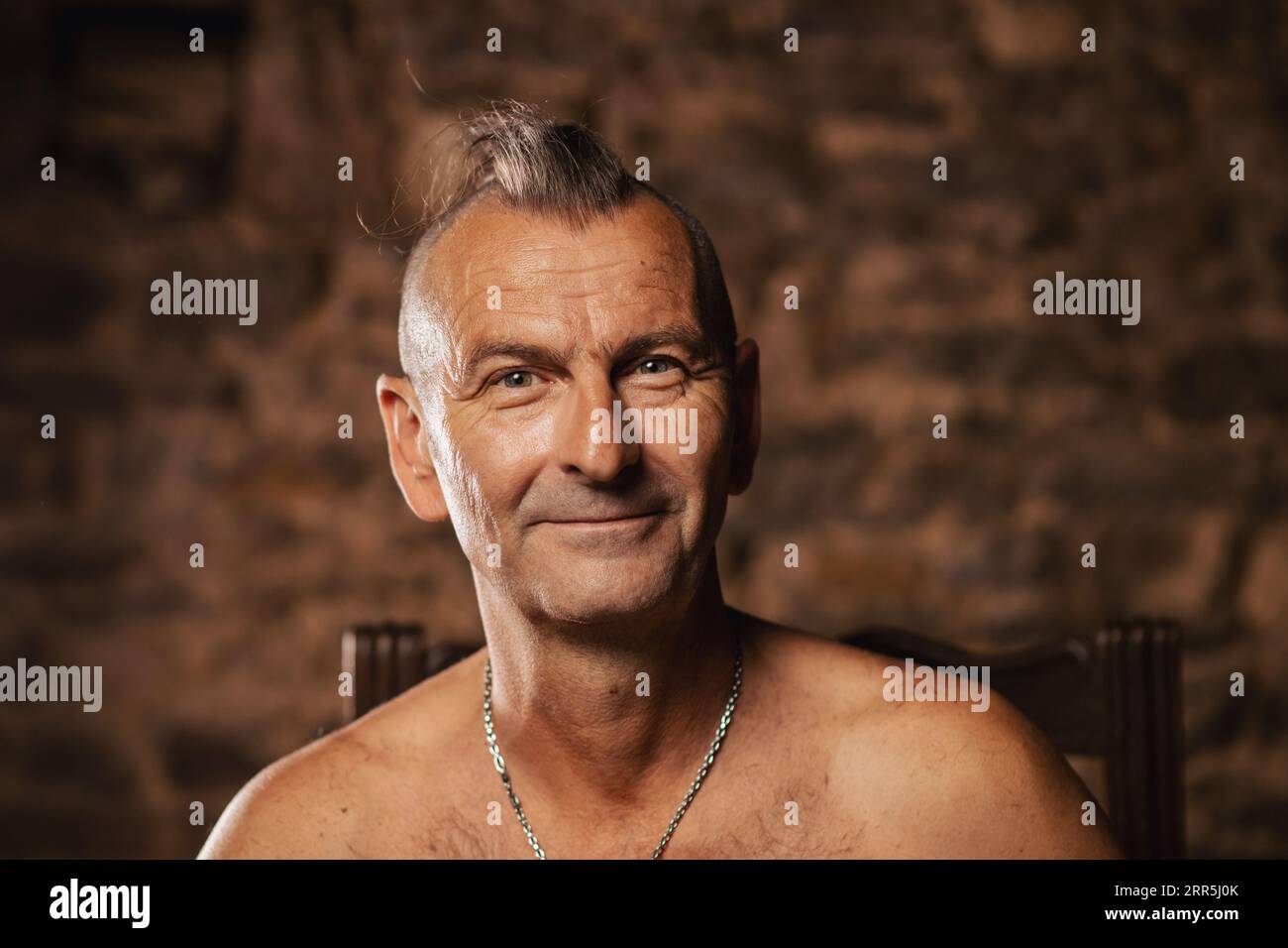 Un homme plus âgé satisfait, âgé de soixante ans, sourit et regarde la caméra. Banque D'Images
