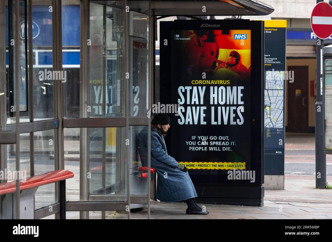 210110 -- LONDRES, le 10 janvier 2021 -- Une personne portant un masque facial est assise à côté d'un panneau publicitaire lisant Stay Home Save Lives à un arrêt de bus à Londres, en Grande-Bretagne, le 10 janvier 2021. Les décès liés au coronavirus en Grande-Bretagne ont dépassé 80 000 samedi avec 1 035 autres signalés dans le pays. BRETAGNE-LONDRES-COVID-19-CAS HanxYan PUBLICATIONxNOTxINxCHN Banque D'Images