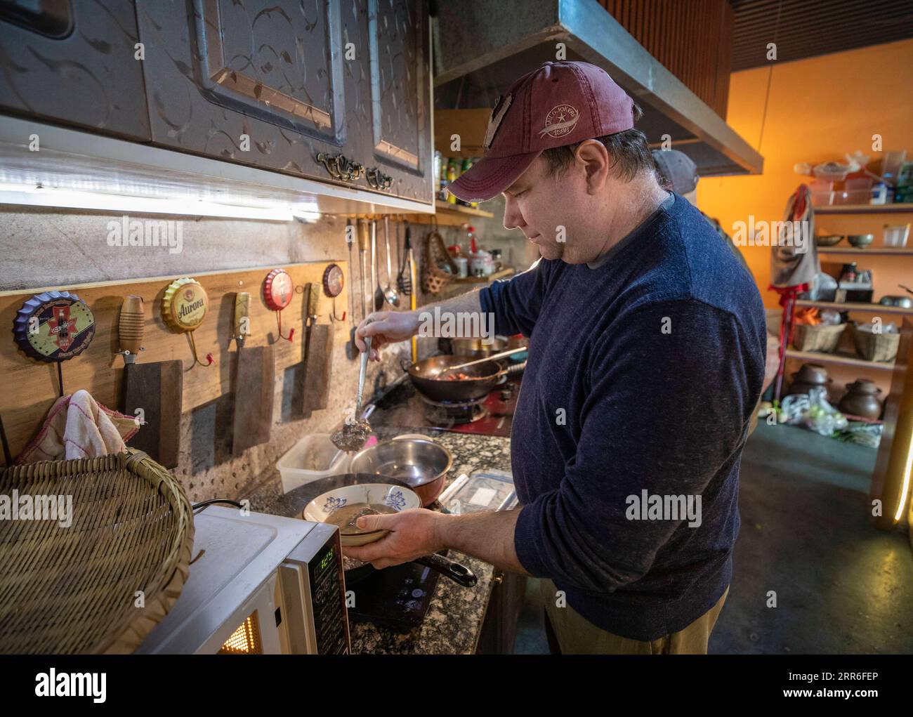 210212 -- CHONGQING, le 12 février 2021 -- Benjamin cuisine à la cuisine pour un festin pour saluer le nouvel an lunaire chinois à Chongqing, dans le sud-ouest de la Chine, le 10 février 2021. Benjamin, un américain vivant dans le sud-ouest de la Chine à Chongqing, est maintenant une célébrité sur Internet avec plus de 900 000 abonnés sur les réseaux sociaux. Benjamin aime le hot pot de Chongqing, peut faire le jeu traditionnel de devinette de Chongqing, et peut parler couramment le dialecte de Chongqing. Ses clips vidéo mettant en scène la vie à Chongqing sont devenus viraux en ligne. En 1994, Benjamin est venu à Chongqing pour étudier. Plus tard, il devient professeur d'anglais à Sichuan International Stu Banque D'Images