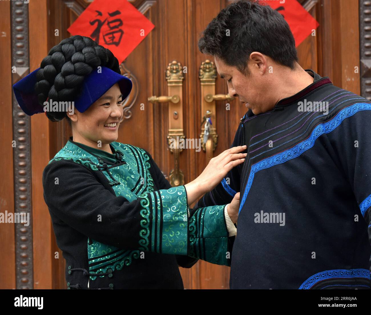 210218 -- CHENGDU, le 18 février 2021 -- Bamu Yubumu aide son mari Wuqi Shiqie avec son manteau dans le comté de Yuexi de la préfecture autonome de Liangshan Yi dans la province du Sichuan du sud-ouest de la Chine, le 17 février 2021. Bamu Yubumu était connue comme une mère migrante dans une photo emblématique lors d'une course de voyage au Festival du printemps il y a 11 ans. Récemment, elle et son mari Wuqi Shiqie se sont lancés dans leur nouvelle carrière de culture de concombres de mer dans la province côtière du Fujian. Au cours des vacances de cette année au Festival du printemps, Bamu et son mari sont retournés dans leur ville natale dans le sud-ouest du Sichuan pour une visite. En pleine saison Banque D'Images