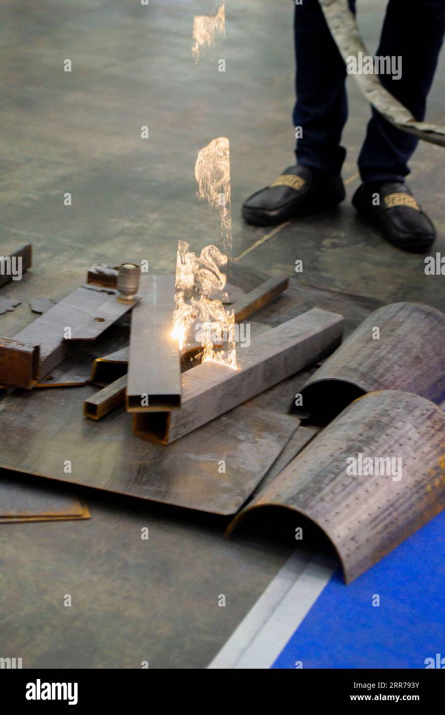 Nettoyage laser de métal. Enlèvement industriel de la rouille de la surface métallique avec faisceau laser. Homme nettoyant la surface de la corrosion avec la machine de nettoyage de métal laser. Rouille de nettoyage laser industriel du métal. Banque D'Images