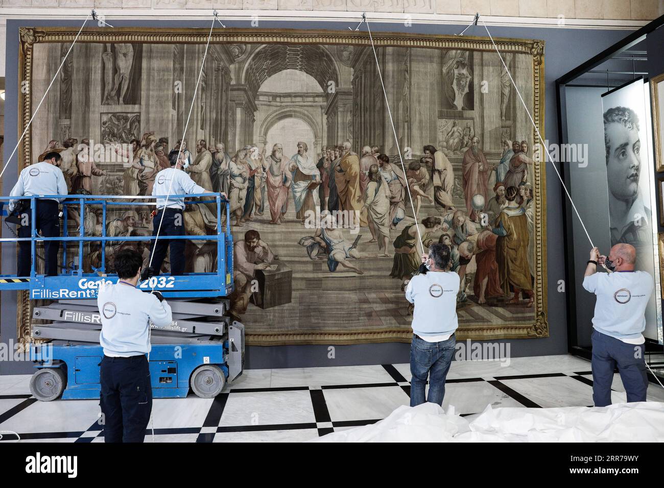 210322 -- ATHÈNES, le 22 mars 2021 -- des travailleurs accrochent une tapisserie représentant l'école d'Athènes à l'intérieur du Parlement grec à Athènes, en Grèce, le 22 mars 2021. Une rare tapisserie du 18e siècle représentant l'artiste italien de la Renaissance Raphaël, chef-d'œuvre de l'école d'Athènes, a été exposée au Parlement grec lundi. L'œuvre, reproduction de la fresque de Raphaël à l'intérieur du Musée du Vatican, a été prêtée à la Grèce à l'occasion du 200e anniversaire du début de la guerre d'indépendance grecque, qui sera célébré ce jeudi. /Document via Xinhua GRÈCE-ATHÈNES-FRANCE-TAPISSERIE-PRÊTÉE G Banque D'Images