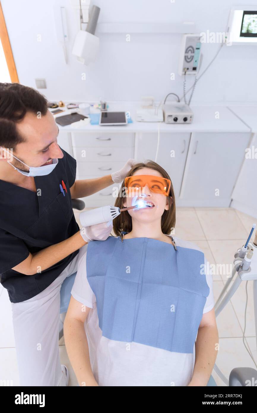 Dentiste masculin heureux vérifiant les dents du patient avec la clinique dentaire d'équipement uv Banque D'Images