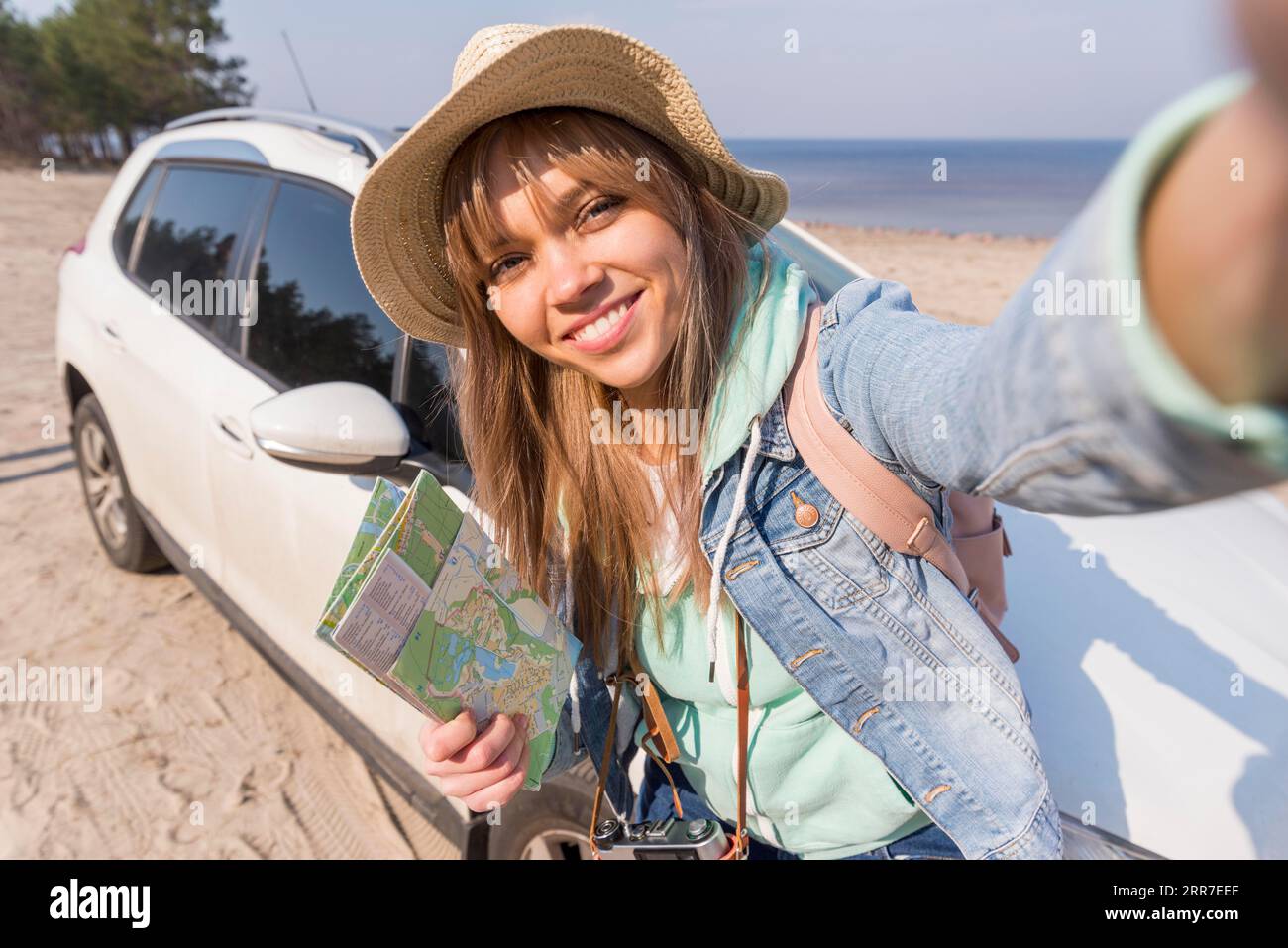 Portrait souriant femme voyageur tenant la carte main prenant selfie avec sa plage de voiture Banque D'Images