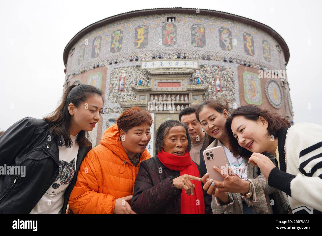 210331 -- NANCHANG, le 31 mars 2021 -- Yu Ermei 3rd L prend des photos avec des touristes devant son palais de porcelaine dans le village de Xinping du comté de Fuliang à Jingdezhen, province du Jiangxi, dans l'est de la Chine, le 18 mars 2021. Yu Ermei, une villageoise de 91 ans qui travaillait autrefois dans une manufacture de porcelaine, a commencé à construire ses palais de porcelaine dans le village de Xinping à partir de 2011. Grâce à ses efforts, quatre bâtiments décorés de porcelaine et de pièces de porcelaine se dressent maintenant dans le village, attirant de nombreux touristes à visiter. CHINE-JIANGXI-JINGDEZHEN-PORCELAINE PALACESCN ZhouxMi PUBLICATIONxNOTxINxCHN Banque D'Images