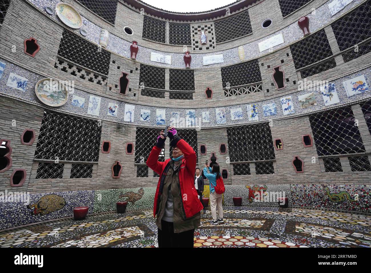 210331 -- NANCHANG, le 31 mars 2021 -- des touristes visitent un palais de porcelaine dans le village de Xinping du comté de Fuliang à Jingdezhen, province du Jiangxi dans l'est de la Chine, le 19 mars 2021. Yu Ermei, une villageoise de 91 ans qui travaillait autrefois dans une manufacture de porcelaine, a commencé à construire ses palais de porcelaine dans le village de Xinping à partir de 2011. Grâce à ses efforts, quatre bâtiments décorés de porcelaine et de pièces de porcelaine se dressent maintenant dans le village, attirant de nombreux touristes à visiter. CHINE-JIANGXI-JINGDEZHEN-PORCELAINE PALACESCN ZhouxMi PUBLICATIONxNOTxINxCHN Banque D'Images