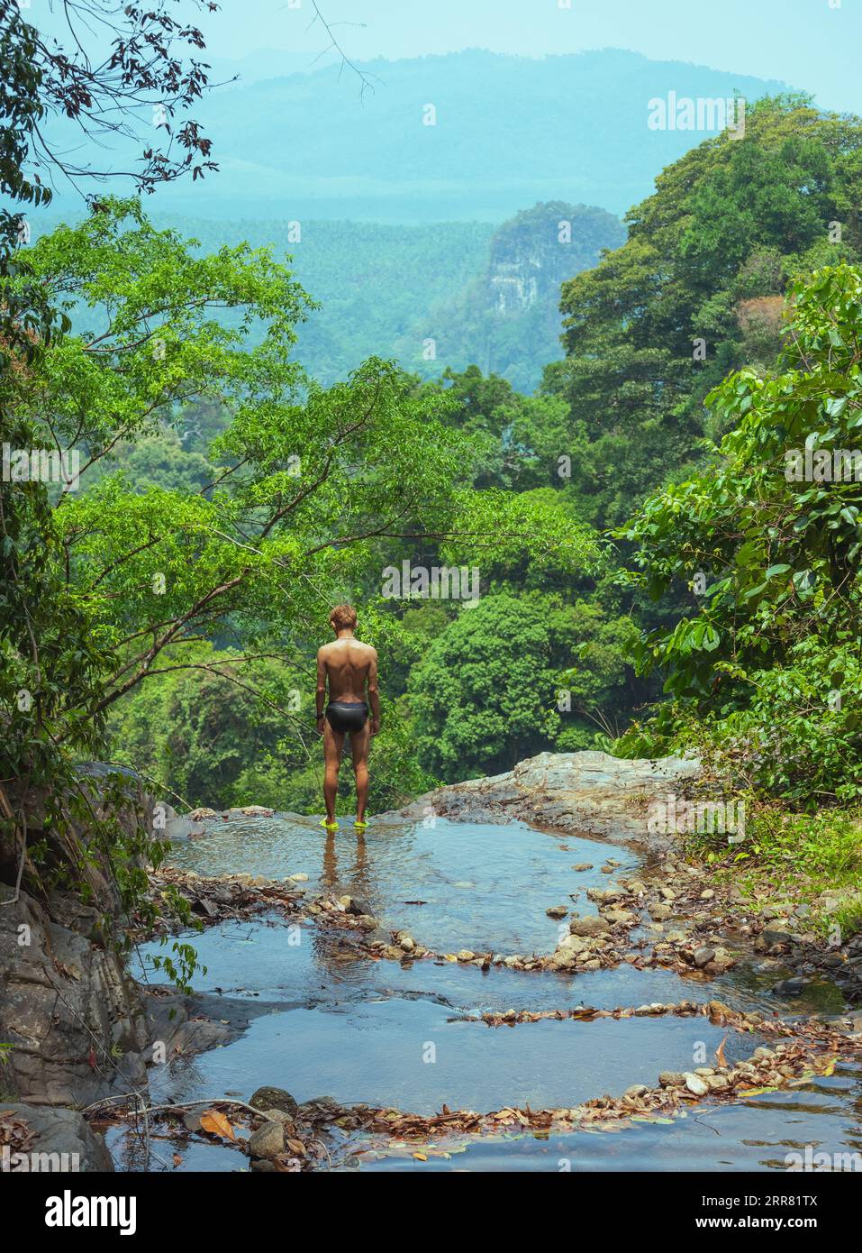 Concept d'unité avec la nature et la santé. Homme asiatique du Sud-est (Thai) en maillot de bain se tient au bord de la cascade dans le parc national de Khao Phanom Bencha Banque D'Images