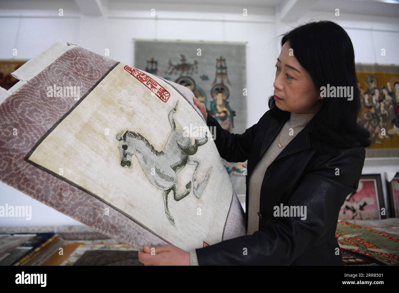 210418 -- TIANSHUI, 18 avril 2021 -- Huang Jingrong voit un tapis de soie dans la salle d'exposition de la Xintian Silk Carpet Company dans la ville de Tianshui, dans la province du Gansu du nord-ouest de la Chine, le 12 avril 2021. La ville de Tianshui, dans la province du Gansu du nord-ouest de la Chine, a une longue tradition de fabrication de tapis en soie. La technique, qui implique plus de 20 procédures, a été inscrite au patrimoine culturel immatériel national en 2014 en raison de sa valeur artistique et de sa complexité. Huang Jingrong, 49 ans, a entrepris son voyage de fabrication de tapisseries de soie à l'âge de 18 ans dans la Xintian Silk Carpet Company. Depuis le premier jour, elle n'est jamais s. Banque D'Images