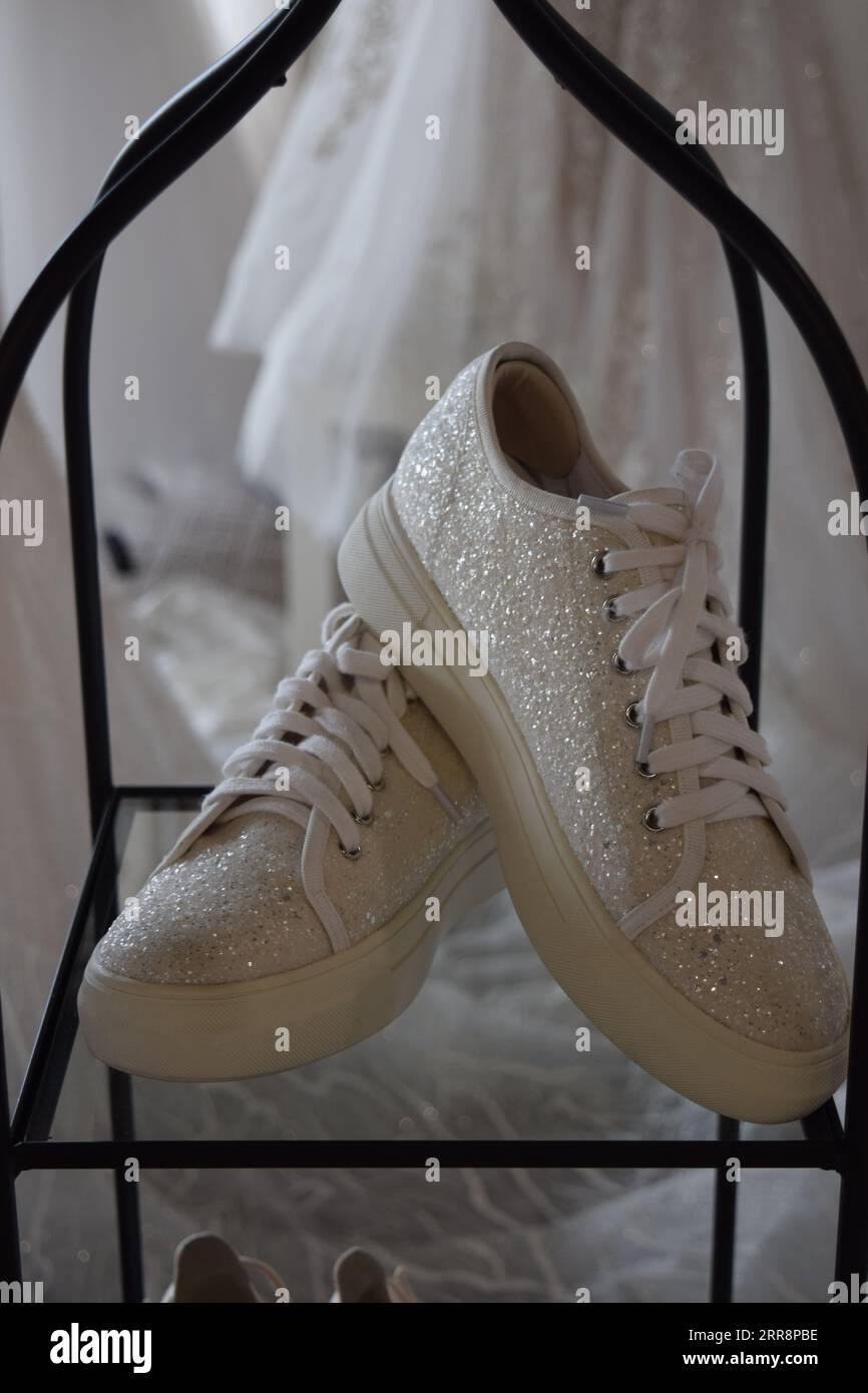 Une paire de chaussures de sport blanches immaculées reposant dans un affichage dans le magasin de mariage Banque D'Images