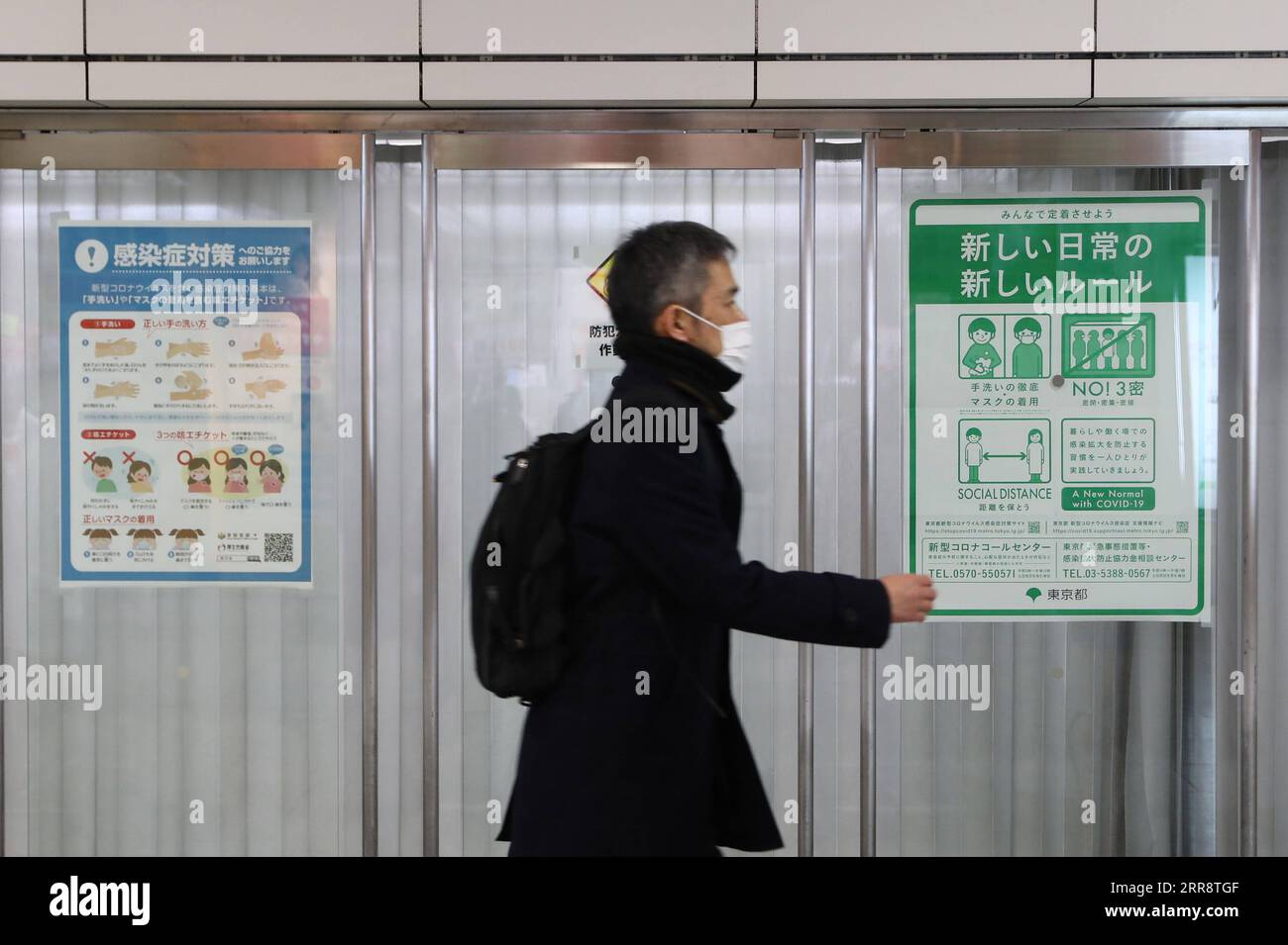 210518 -- TOKYO, 18 mai 2021 -- une photo prise le 22 janvier 2021 montre un piéton portant un masque facial qui passe devant une affiche contenant des informations sur la prévention des épidémies à Tokyo, au Japon. Le produit intérieur brut du Japon au cours de l exercice 2020 a diminué de 4,6 pour cent en termes réels, en baisse pour la deuxième année consécutive, les statistiques gouvernementales ont révélé mardi. Pendant ce temps, les statistiques du gouvernement ont montré que l économie du pays au cours de la période janvier-mars a contracté un taux réel annualisé de 5,1 pour cent par rapport au trimestre précédent, la première baisse en trois trimestres, en raison d un deuxième état d urgence sur le COVID-19 Banque D'Images
