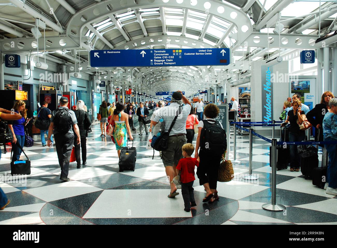 Une famille voyageant se précipite dans le terminal pour prendre leur vol alors qu'ils se promènent autour des autres voyageurs à l'aéroport international O'Hare de Chicago Banque D'Images