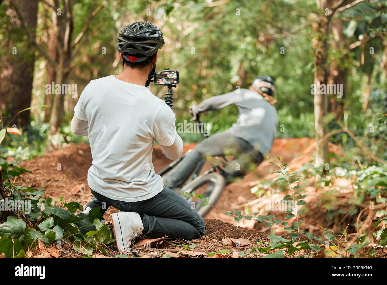 Homme, vélo et forêt avec photographe, vitesse et téléphone pour la course, vélo vidéo ou post sur le blog web. Guy, vélo et enregistrement pour vlog, live Banque D'Images