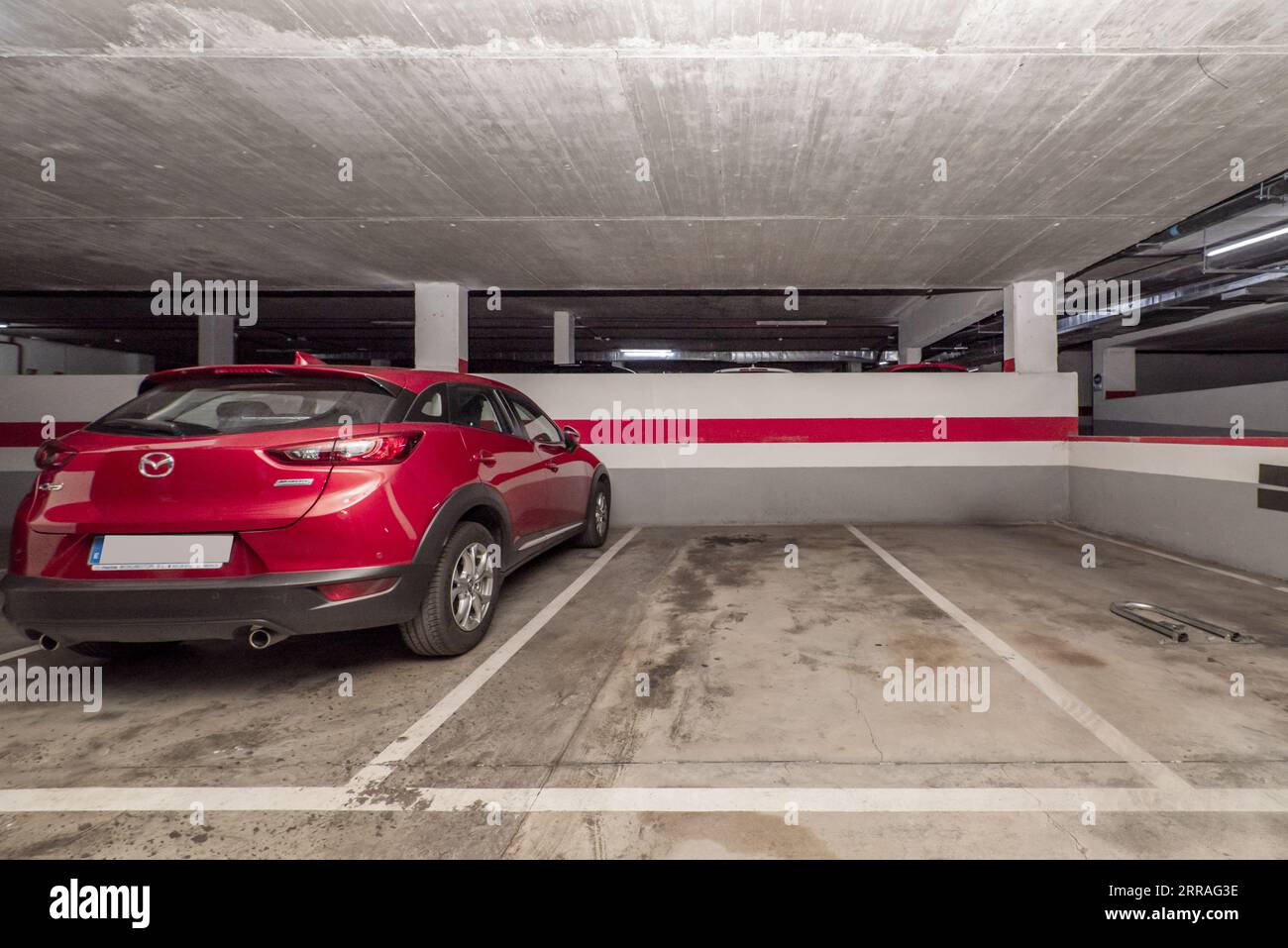 Un parking souterrain avec de nombreux espaces vides délimités par de la peinture blanche sur le sol en ciment Banque D'Images