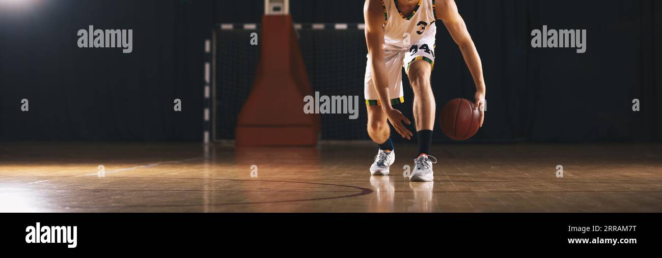 Joueur européen de basket-ball rebondissant balle sur le terrain en bois. Athlète dribbling Basketball sur l'unité d'entraînement Banque D'Images