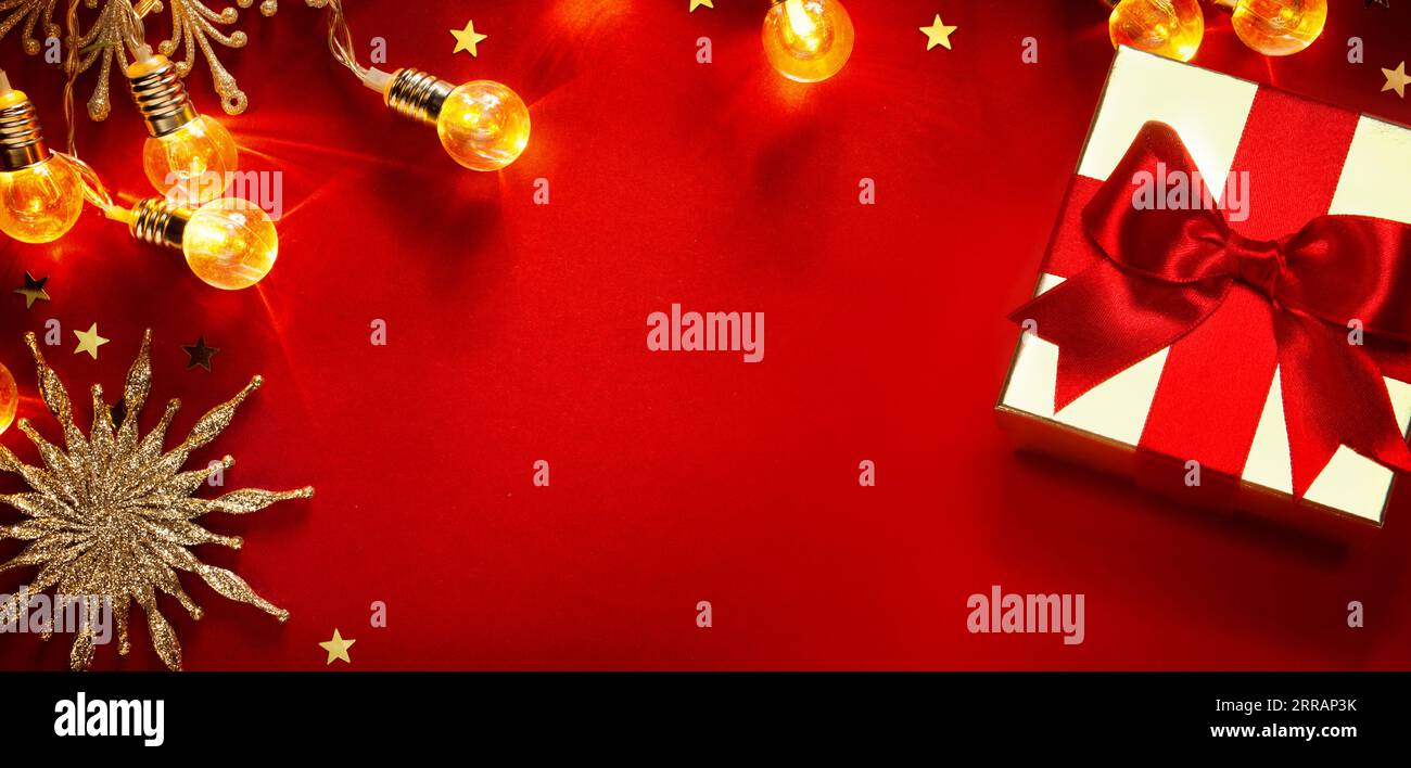 Carte de voeux de Noël ou fond de bannière avec boîte cadeau dorée de noël et décoration d'arbre sur fond rouge Banque D'Images