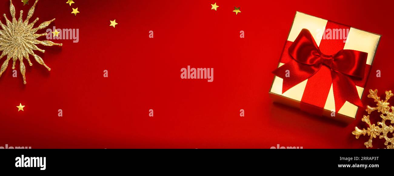 Fond de bannière de Noël ou de carte de vœux avec boîte cadeau de noël et décoration dorée sur fond rouge Banque D'Images