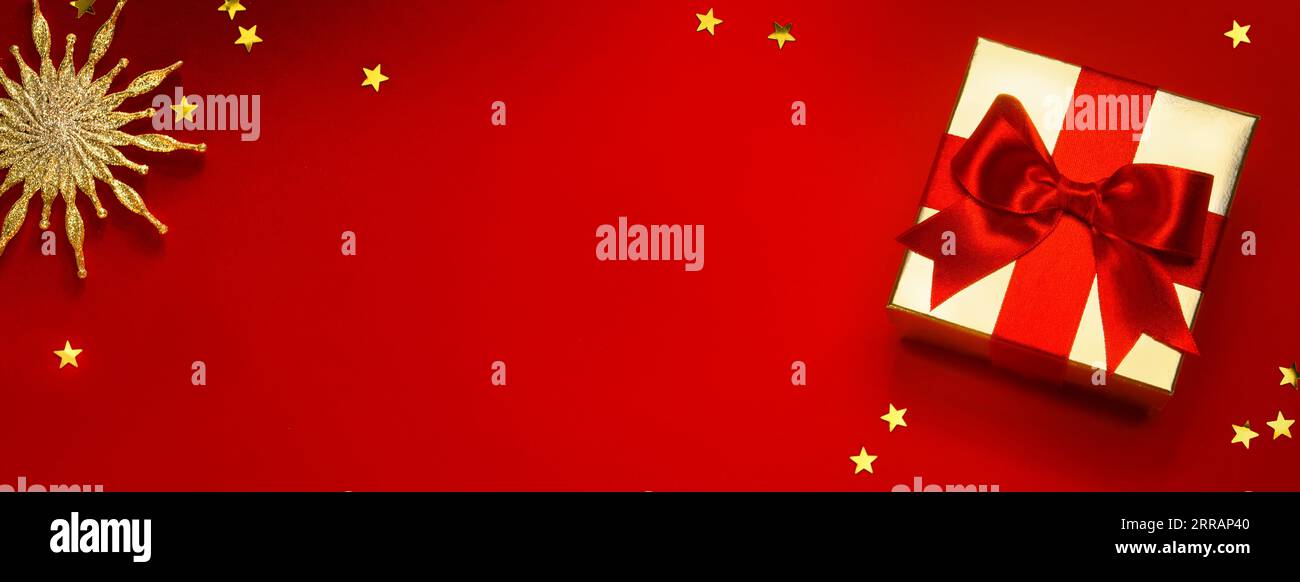 Fond de bannière de Noël ou de carte de vœux avec boîte cadeau de noël et décoration dorée sur fond rouge Banque D'Images