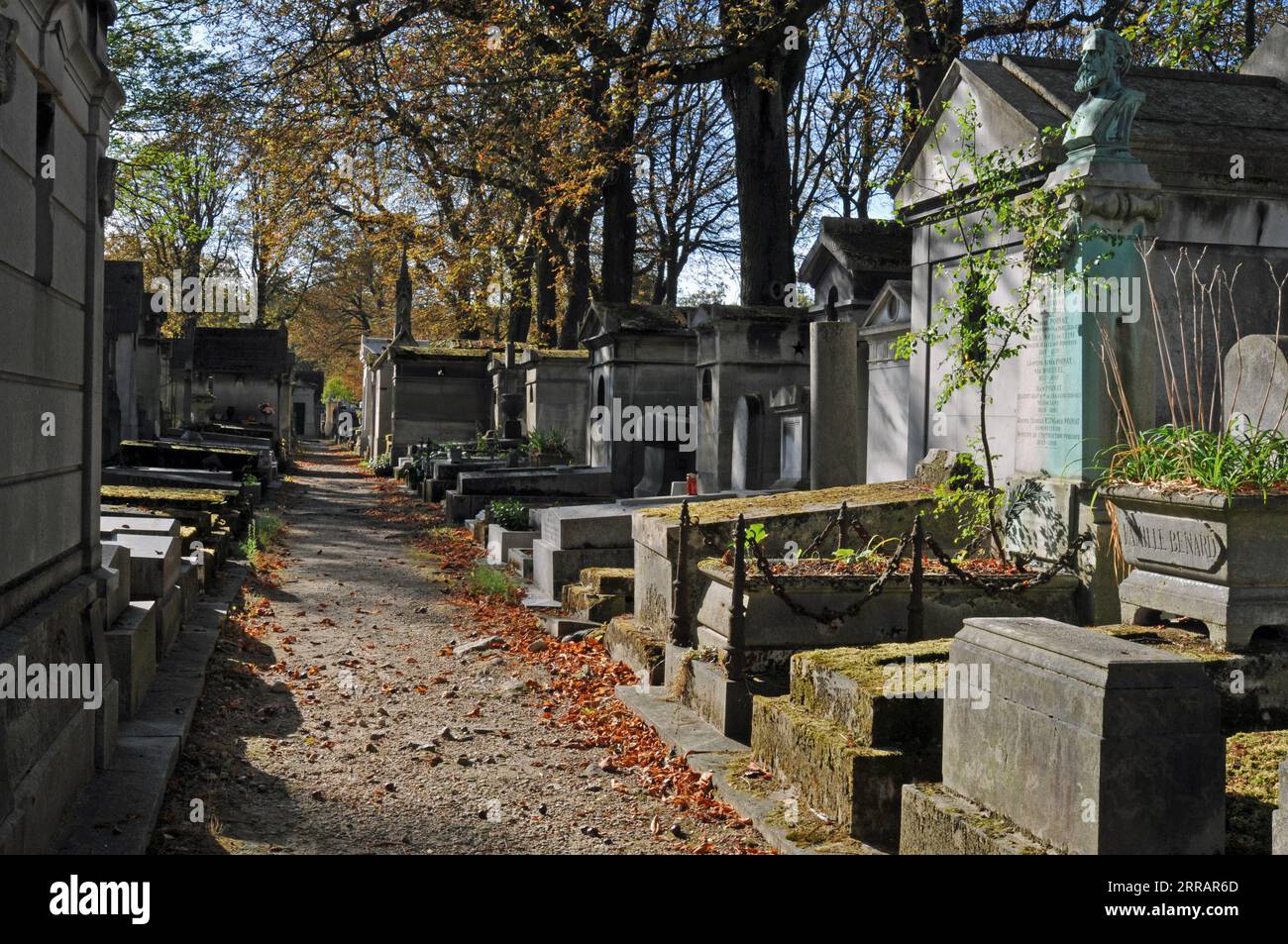 Un chemin de gravier mène devant des tombes et des tombes recouvertes de mousse dans le cimetière historique du Père Lachaise de Paris. Banque D'Images