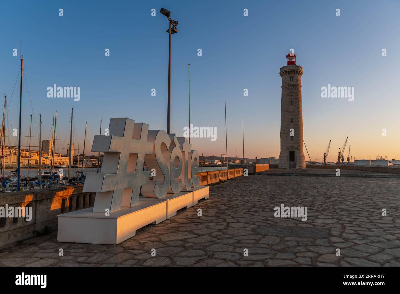 Le mot Sète et le phare de Môle Saint Louis au lever du soleil, en Occitanie, France Banque D'Images