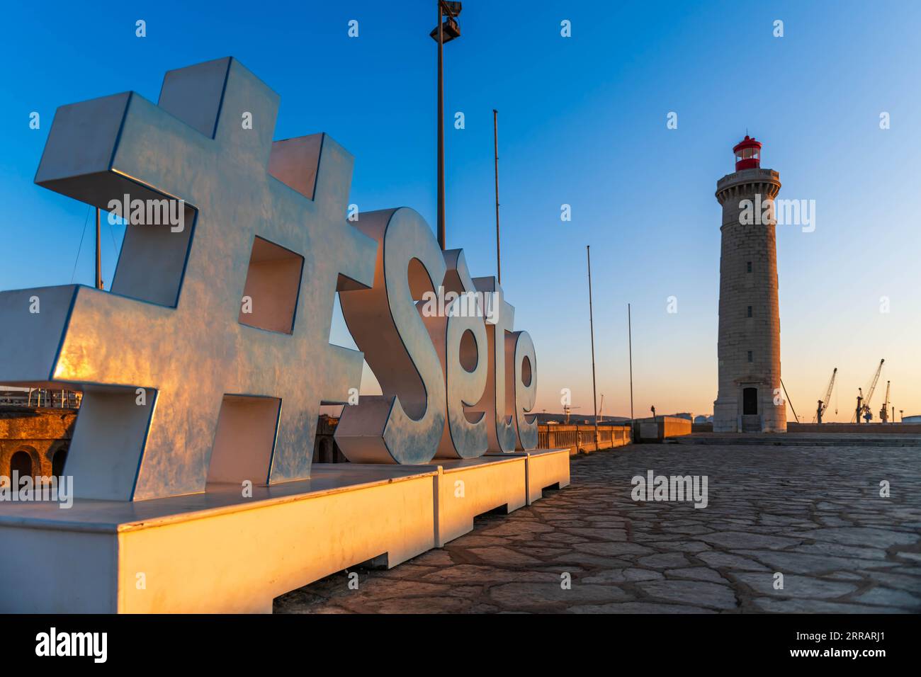 Le mot Sète et le phare de Môle Saint Louis au lever du soleil, en Occitanie, France Banque D'Images