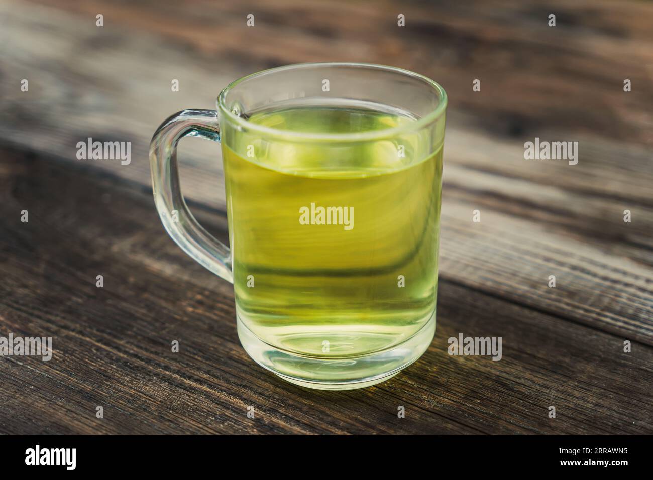 thé dans une tasse en verre sur une table en bois, boisson chaude saine et remède maison contre la toux, les maux de gorge, les problèmes digestifs, la gingivite et la transpiration, vert foncé Banque D'Images