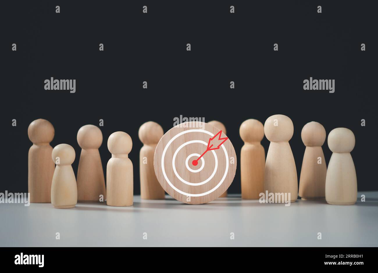 Concept cible des affaires et du personnel dans une entreprise. Poupées en bois debout autour du tableau de fléchettes et des flèches pour créer et cibler objectiv d'affaires Banque D'Images