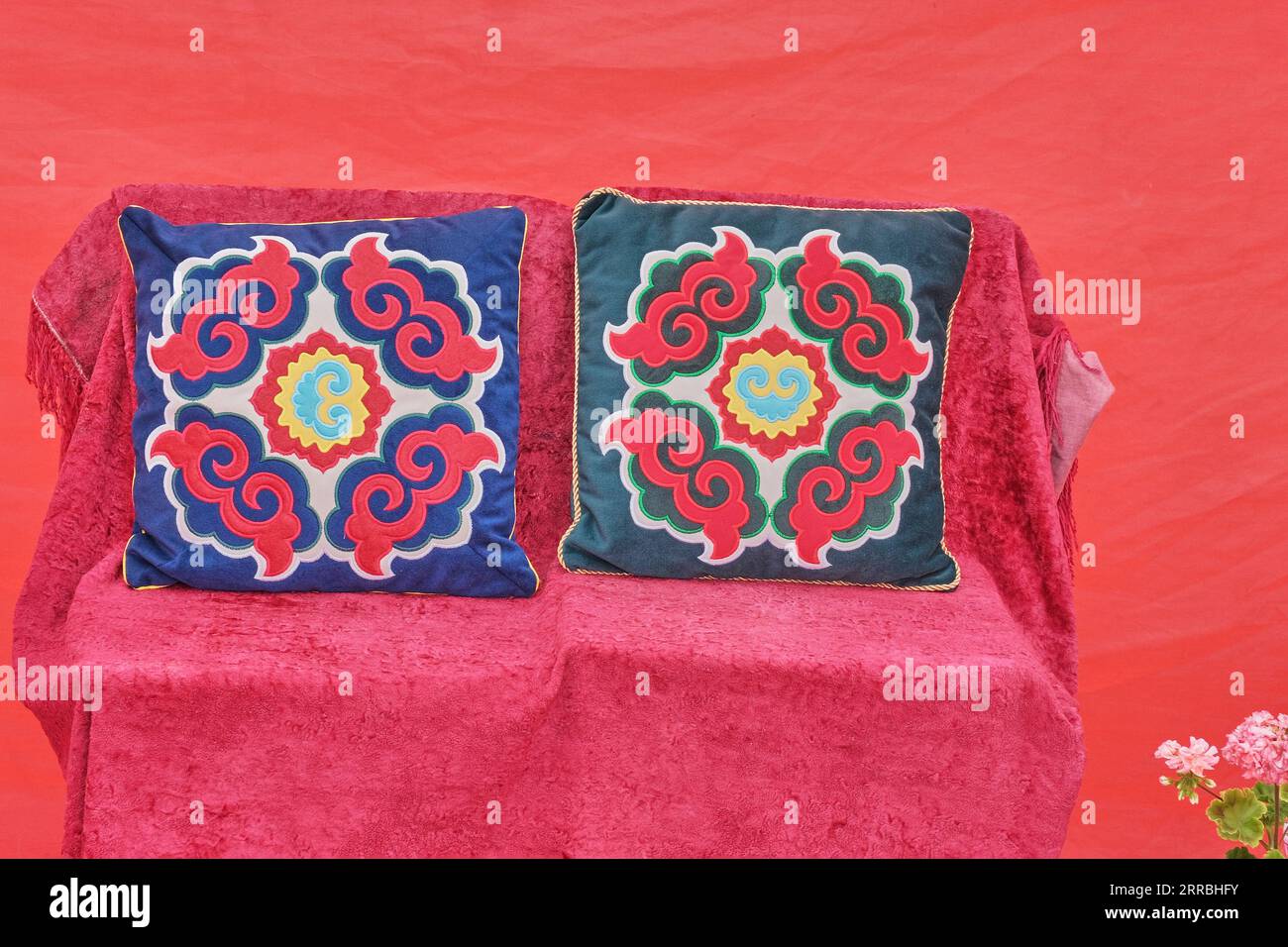 Deux petits oreillers sur fond rose-rouge. Taies d'oreiller colorées avec un motif de plante tatar traditionnel, faites en utilisant la technique de l'applique et embr Banque D'Images