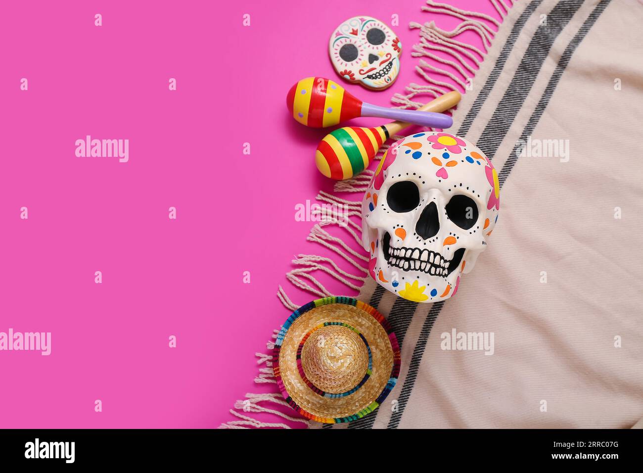 Crânes humains peints pour le jour des morts du Mexique (El Dia de Muertos) avec maracas, sombrero et poncho sur fond rose Banque D'Images