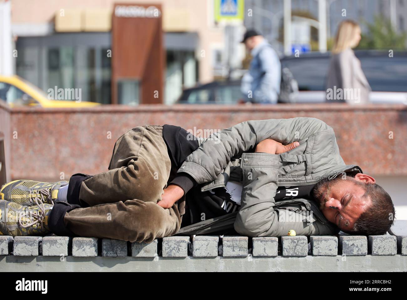 Mendiant dormant dans la rue de la ville. Pauvreté, sans-abri et mendicité Banque D'Images