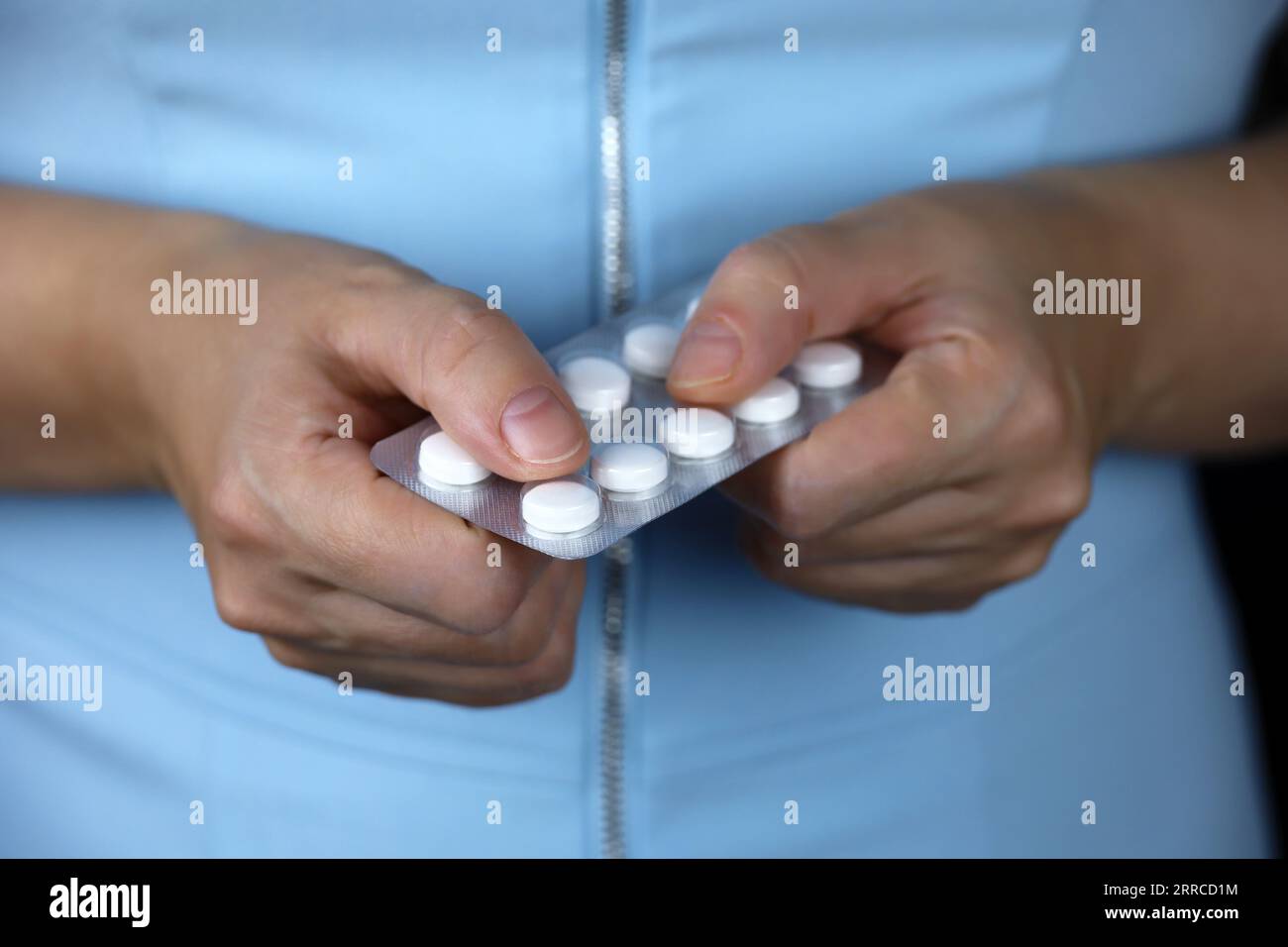 Femme en robe bleue avec des pilules dans ses mains. Concept de prescription médicale, minceur ou vitamine Banque D'Images