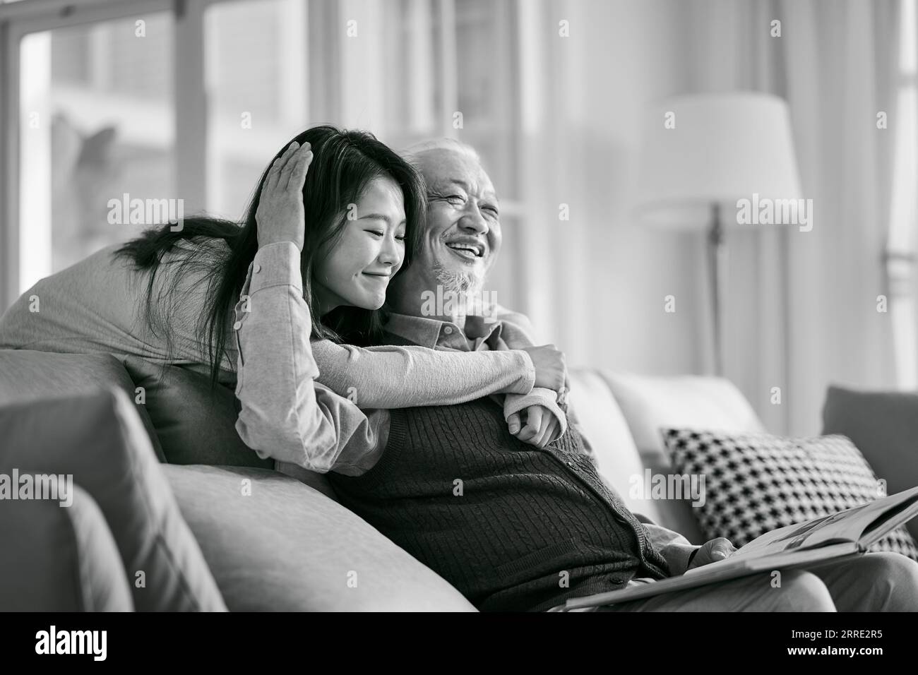 fille adulte asiatique et père aîné appréciant la conversation et le bon temps à la maison, noir et blanc Banque D'Images