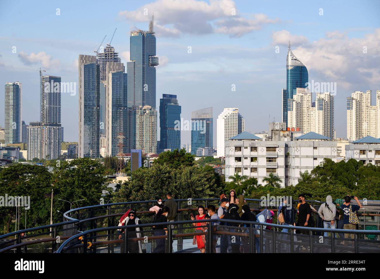 220123 -- JAKARTA, le 23 janvier 2022 -- les gens apprécient la vue sur la ville sur la passerelle du parc Senayan à Jakarta, Indonésie, le 23 janvier 2022. Le 18 janvier, les législateurs indonésiens ont adopté une loi sur la relocalisation de la capitale de la nation sur l île de Kalimantan, dont le pays partage des frontières avec la Malaisie et Brunei, à partir de l île la plus peuplée de Java. Nusantara, la nouvelle capitale, sera construite dans deux districts du Kalimantan oriental - Penajam Paser Utara et Kutai Kartanegara. Il devrait occuper environ 256 000 hectares de terres. Nusantara servira de centre du gouvernement, tandis que Jakarta W Banque D'Images