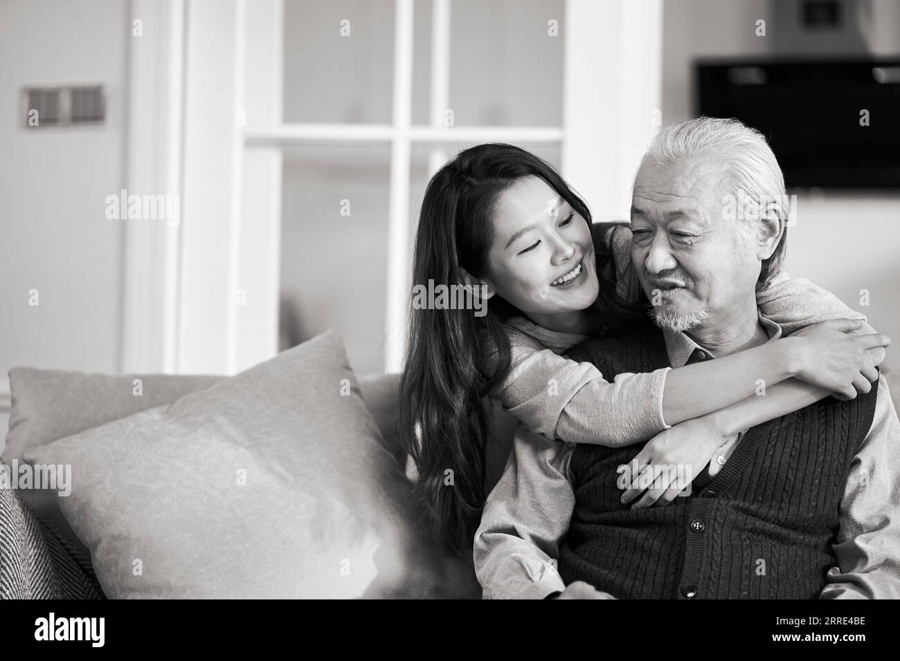 père aîné asiatique et fille adulte assis sur le canapé dans le salon à la maison profitant d'une conversation agréable, noir et blanc Banque D'Images