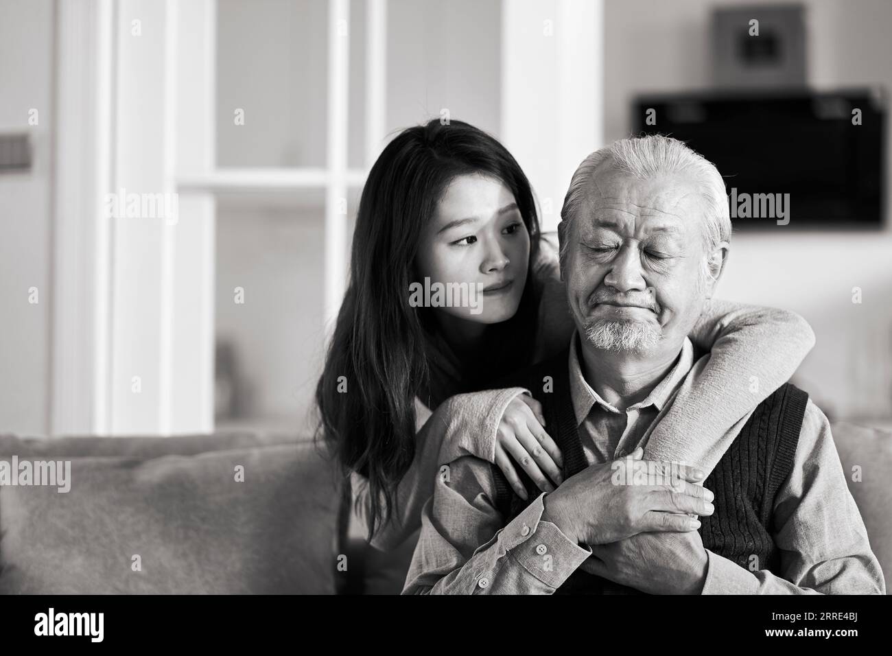 triste père asiatique senior assis sur le canapé dans le salon à la maison consolé par une fille adulte, noir et blanc Banque D'Images