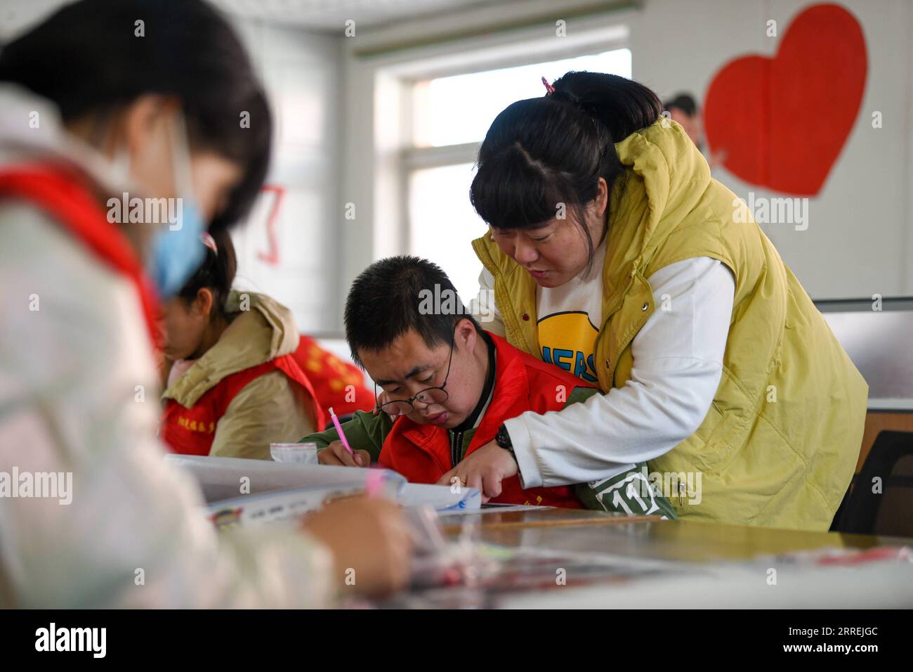 220304 -- TIANJIN, le 4 mars 2022 -- Tian Lichao enseigne à un jeune handicapé de réaliser une peinture décorative au point de croix dans une base d'emploi pour handicapés dans le district de Baodi, dans le nord de la Chine, Tianjin, le 1 mars 2022. Dans un complexe spécial de la ville de Shigezhuang, district de Baodi, 49 jeunes handicapés âgés en moyenne de moins de 23 ans travaillent et vivent ici. Le retard mental, la déficience visuelle et d'autres handicaps les ont autrefois rendus inférieurs. Cependant, avec l'aide de Tian Lichao, ils deviennent de plus en plus confiants. Un jour en 2016, Tian Lichao a rencontré une fille perdue avec une déficience intellectuelle sur t Banque D'Images