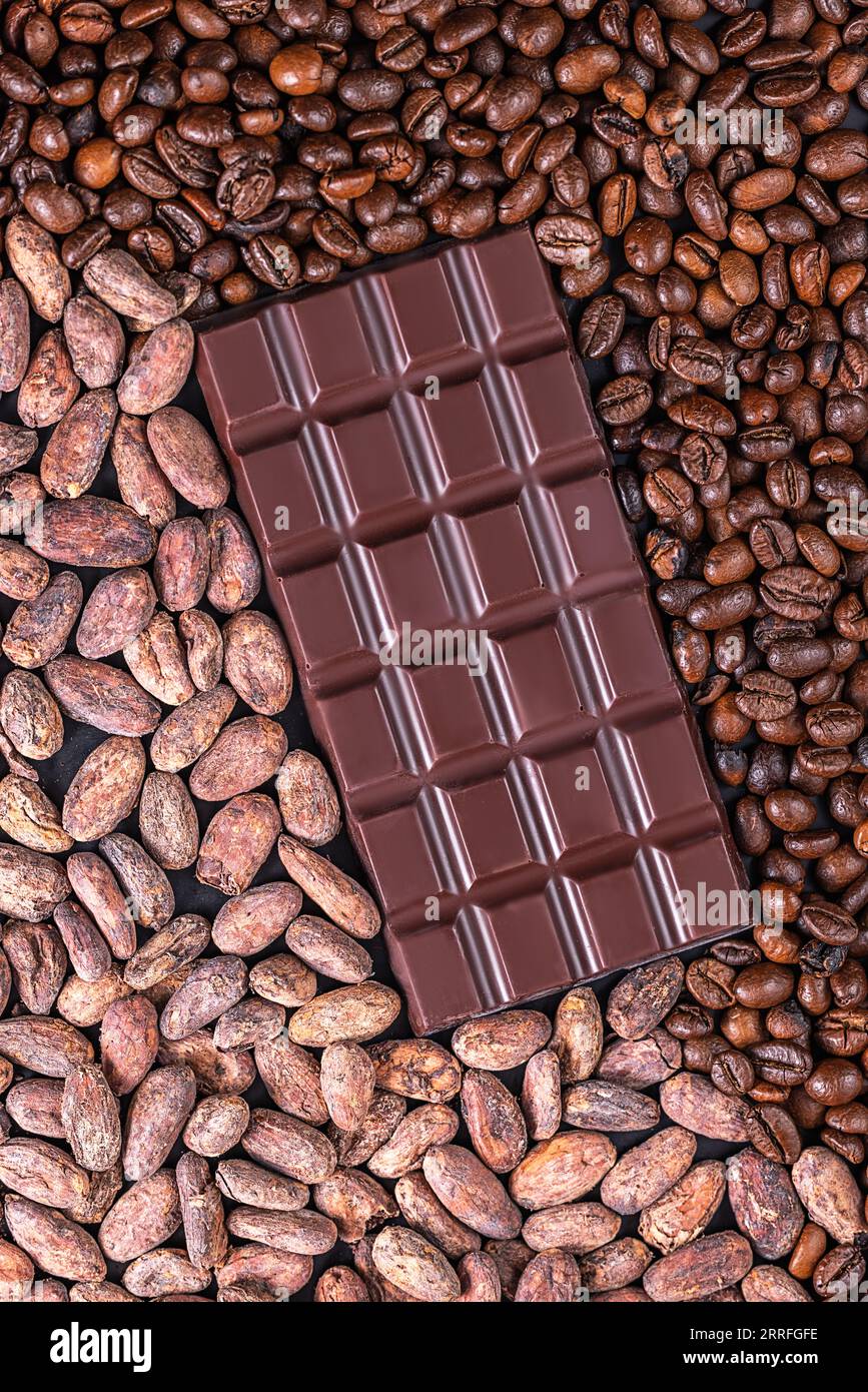 Barre de chocolat noir biologique, pointes de cacao et grains de café en arrière-plan Banque D'Images