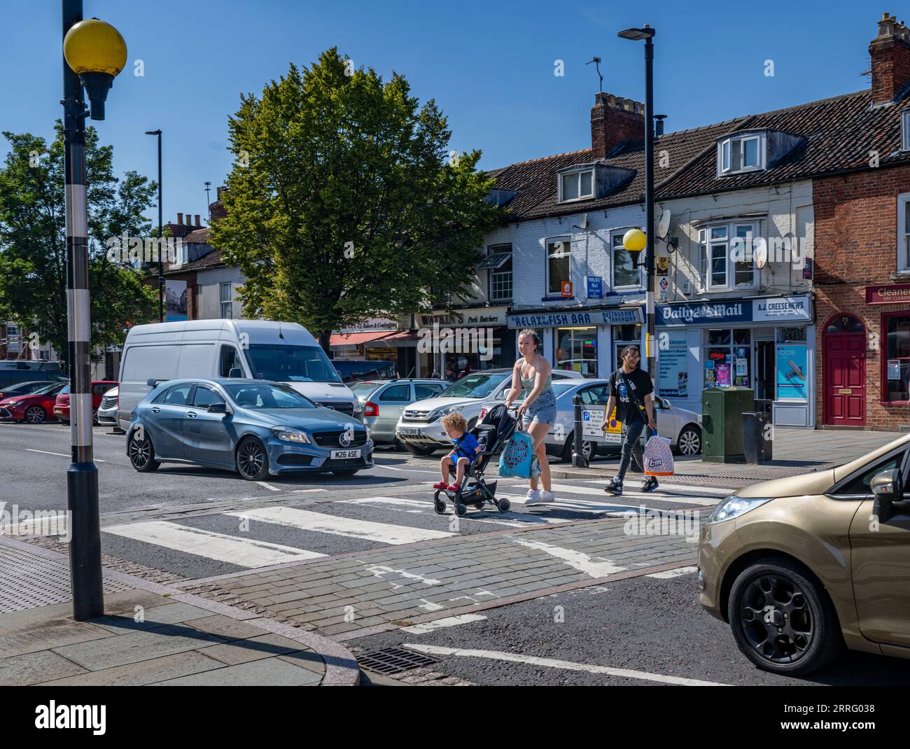 Grantham Lincolnshire - passage Zebra ou un passage pour piétons dans une rue très fréquentée avec une jeune mère traversant avec son enfant dans une poussette Banque D'Images