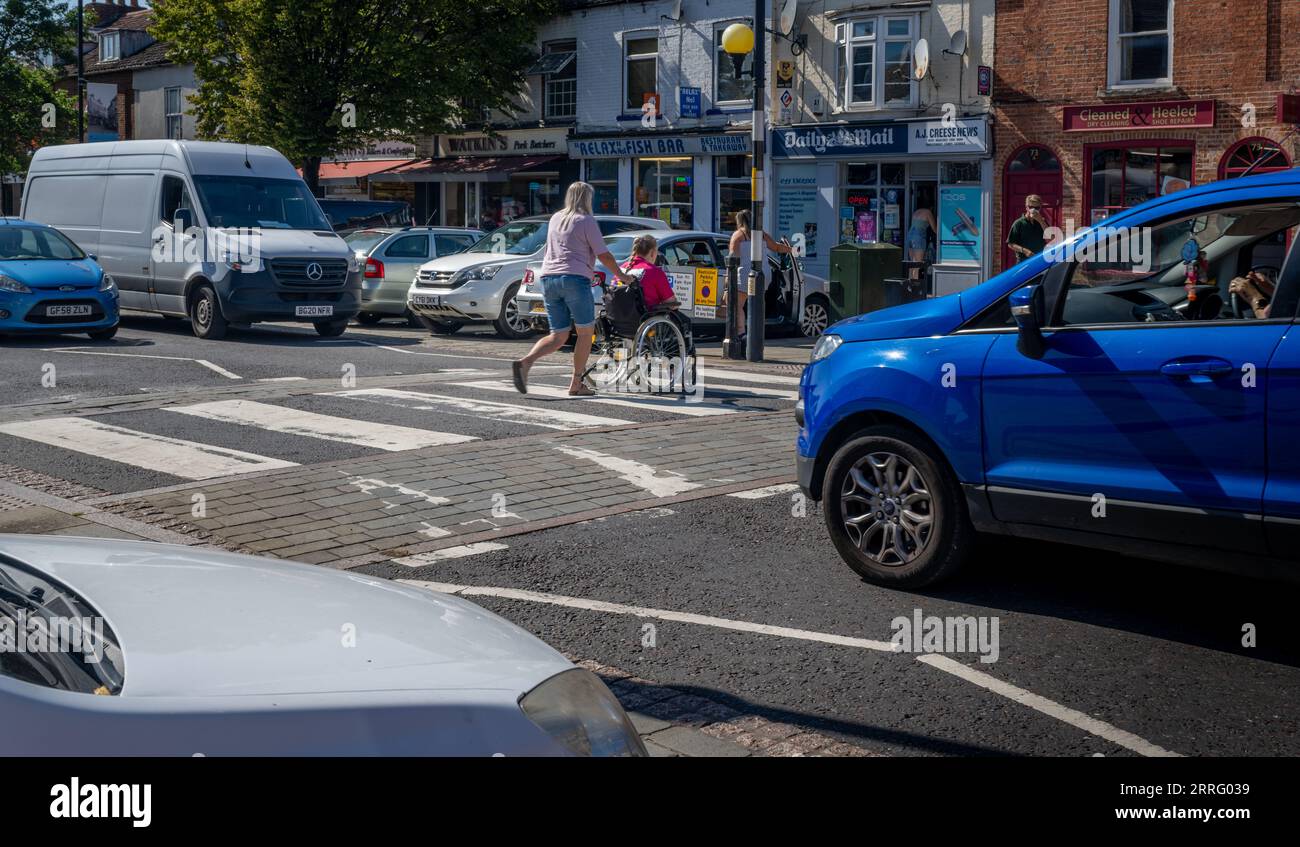 Grantham Lincolnshire - passage à niveau Zebra ou un passage pour piétons sur une rue très fréquentée avec une personne en fauteuil roulant poussé à travers la route Banque D'Images