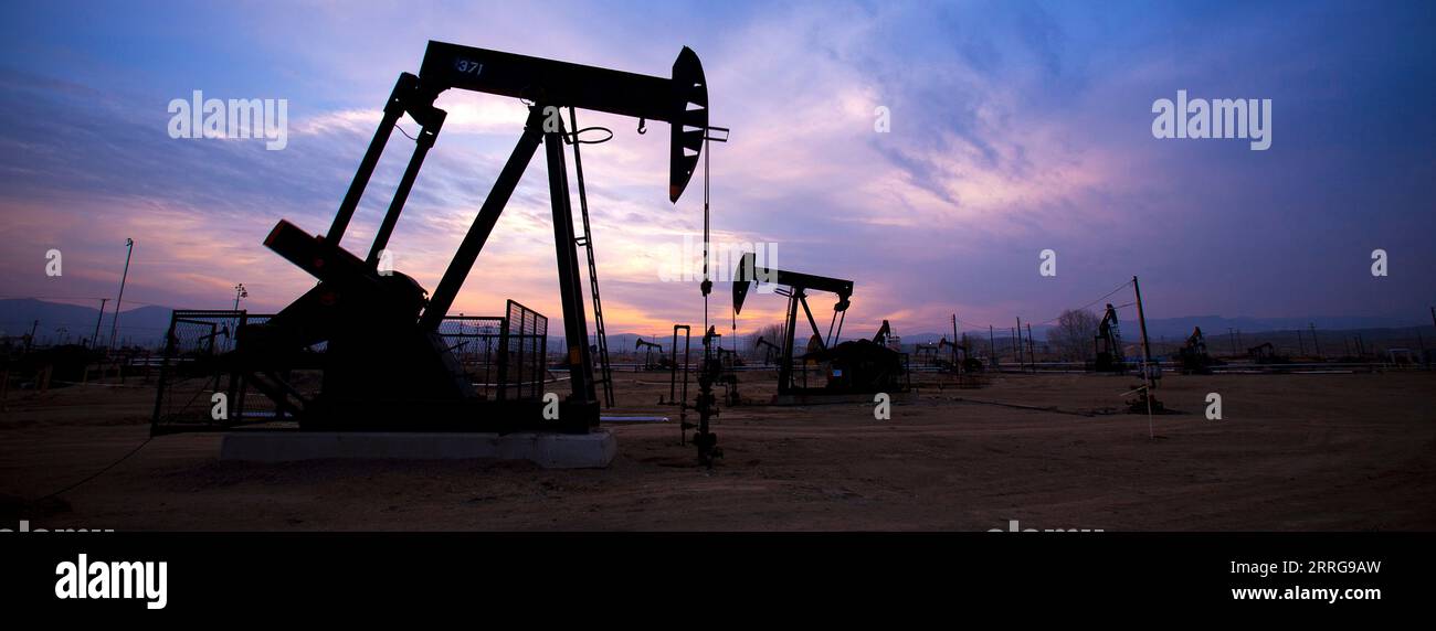 Silhouette de derricks de pétrole au coucher du soleil dans le champ de pétrole Midway-Sunset situé dans le comté de Kern, San Joaquin Valley, Californie aux États-Unis Banque D'Images