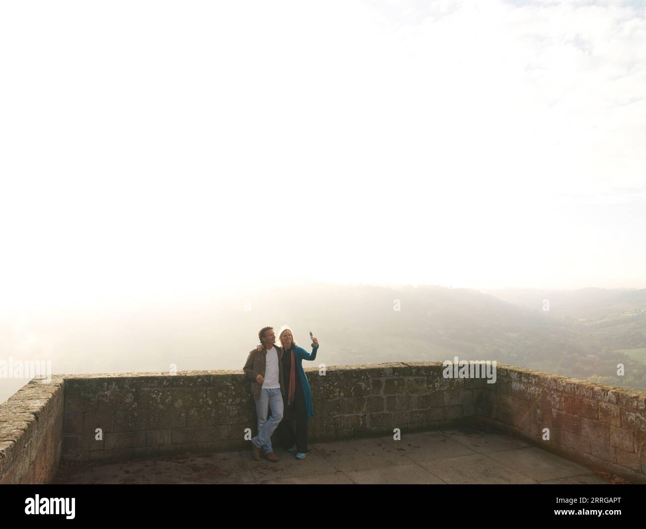 Couple se pencher contre le vieux promantoire de mur de roche et prendre selfie Banque D'Images
